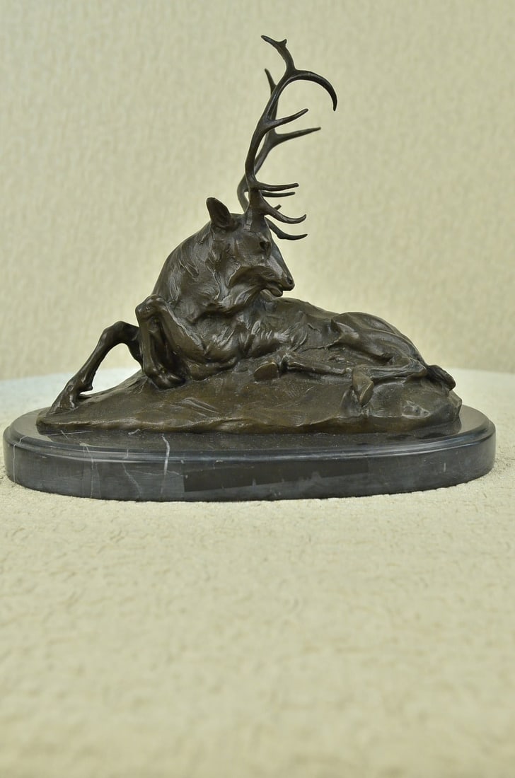 Deer Bronze Sculpture: This old elk takes a rest from the summer day heat in a cool grassy area. He lies down and reaches his massive head around his back to scratch and itch that has been bothering him. He is old and his c