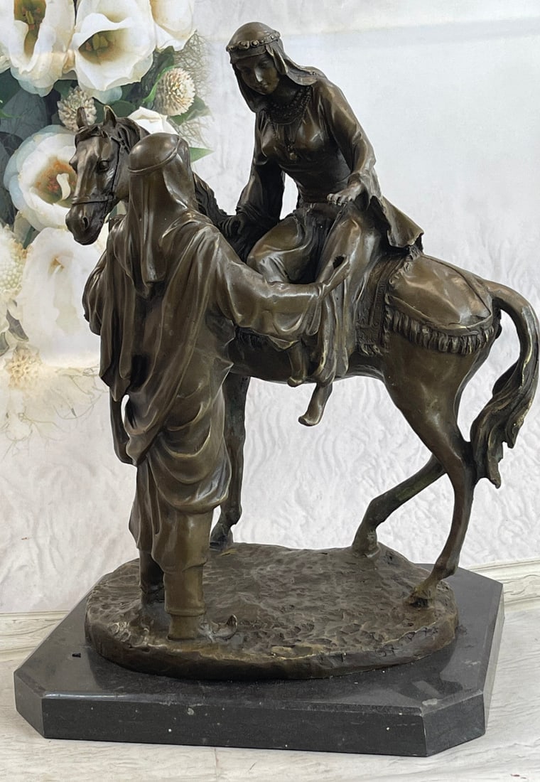 A Man Helping his wife Bronze Statue: A man stands beside his horse assisting his wife off the Horse. She reaches out her hand to grasp his and ease her way down. They are both dressed in traditional Arabian garments and headdresses. Jewe