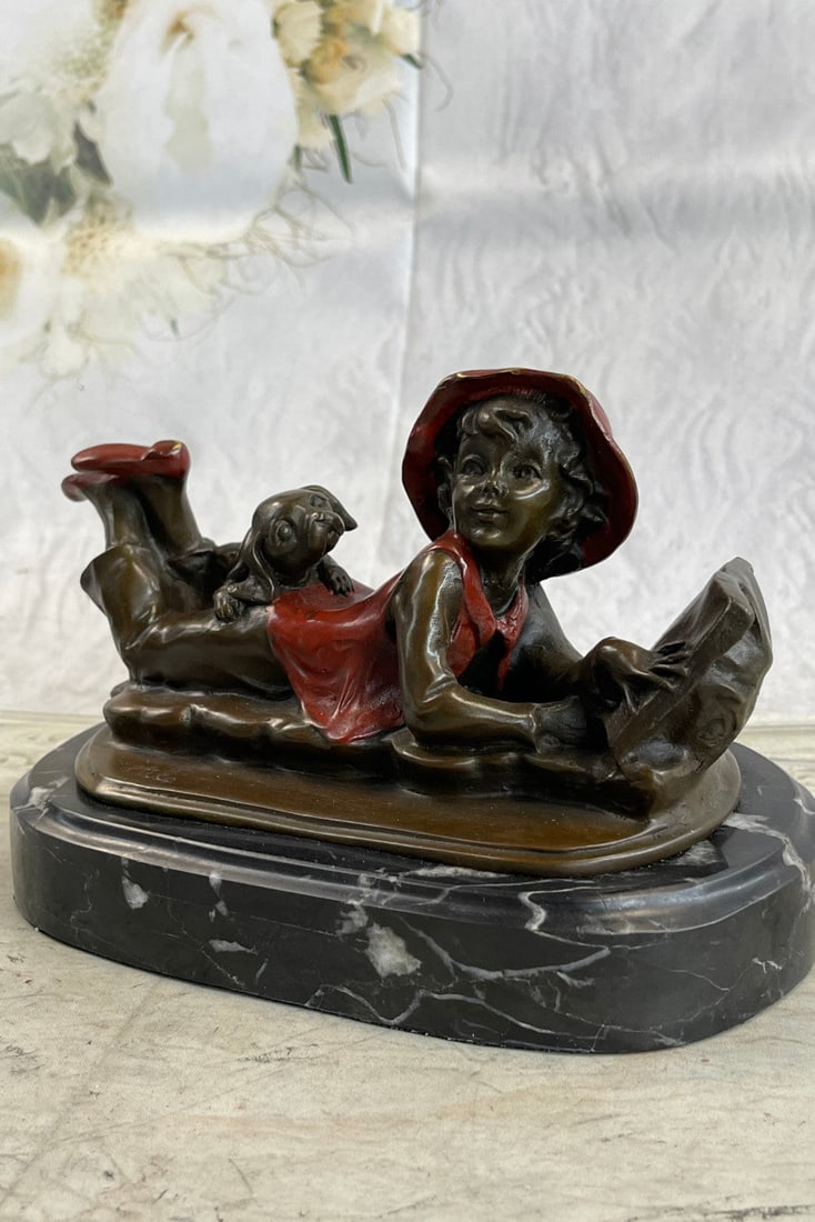 Girl With Dog Bronze Sculpture: This lost-wax cast bronze sculpture is of a boy who was pleasantly startled by the viewer due to his concentration in his open book. He lies belly down in perhaps a field, under a tree, on a beautiful