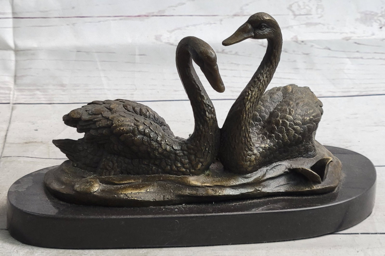 Two Beautiful Swans Bronze Sculpture: Two beautiful swans are facing each other as they float. Swans are a symbol of balance, grace, and elegance. The artist has designed them wonderfully, paying attention to the curves on the feathers