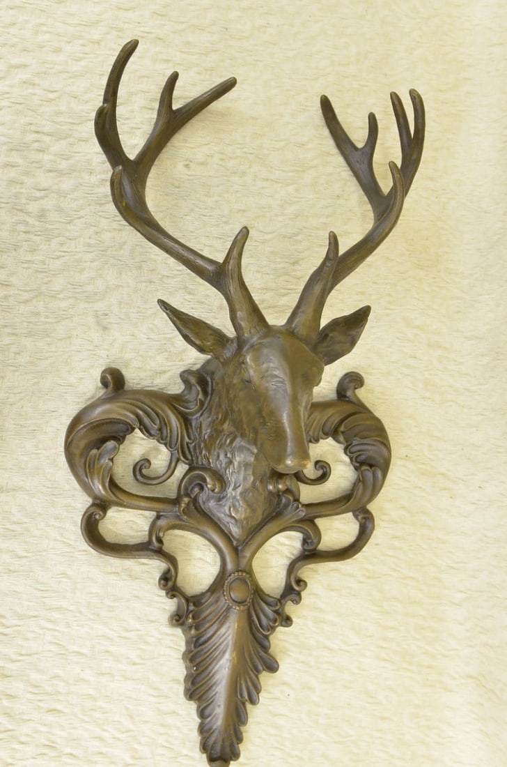Wildlife Elk Head Bust Bronze Sculpture: This is a bronze Deer head wall mount, a hunter trophy, of a magnificent creature. Its vivacity mummified for ages, the deer looks out under a crown of tall, a reminder of wild beauty. The deer is