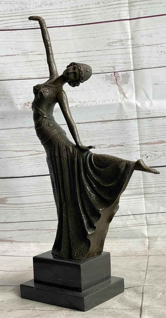 Elegant Dancer in Arabesque Bronze Sculpture: An elegant dancer extends her long leg out in an arabesque. Her long vibrant dress extends with her. She raises softly and gently to the sky. Her head tilts along with the movement. This is a very bea