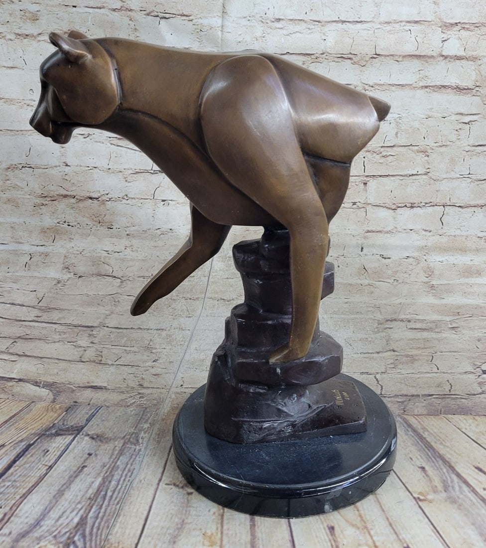 Cougar Female Lion Bronze Sculpture: Her muscles flex as she poses on a large rock. This Sculpture draws you into the action and lets your imagination run wild as you join her on her walk across the wide-open plains of the outdoors. This