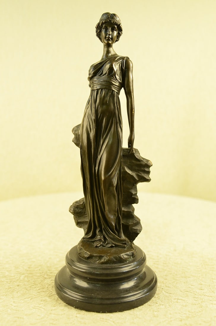 Roman Lady Bronze Statue: A young maiden steals a leisurely moment in the day to relax. She leans against a rock and gazes into the distance. She wears a long goddess-like dress that slouches off her shoulder and drapes over h