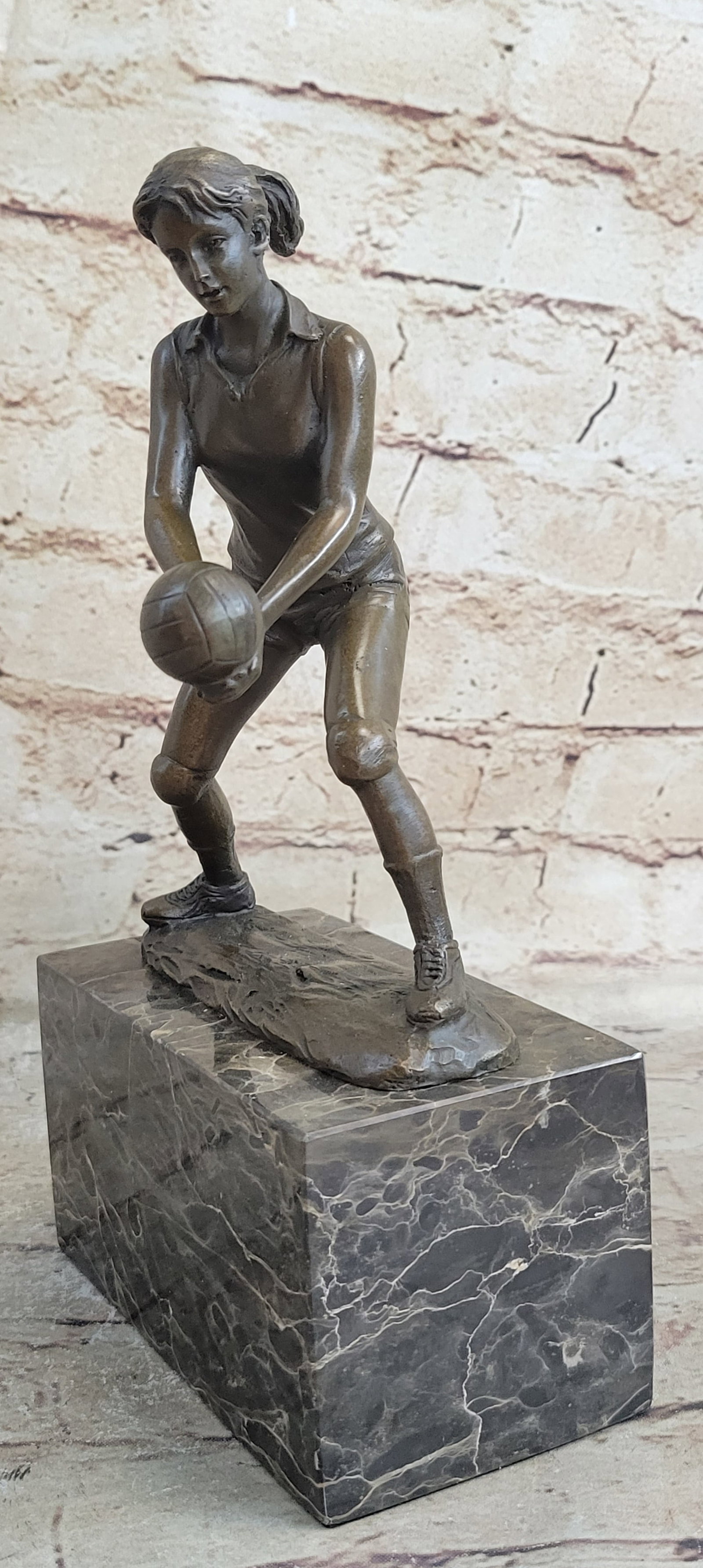Girl Volleyball Player Bronze Figurine: She races across the court balls up her fists closely together and spikes the ball. Her knees bend slightly beneath her as she strikes the ball. Her ponytail swings behind her. She is well toned and