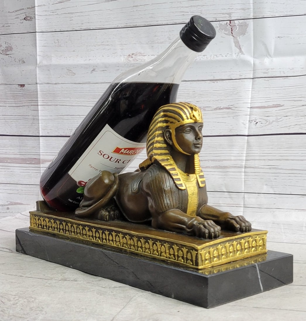 Win Holder Creature Sphinx Egyptian Bronze Sculpture: A sphinx is a widely known mythological creature with a lion body and a human head. This image is highly revered in Egyptian and Greek art. The body is of a powerful and strong lion laying on its stom