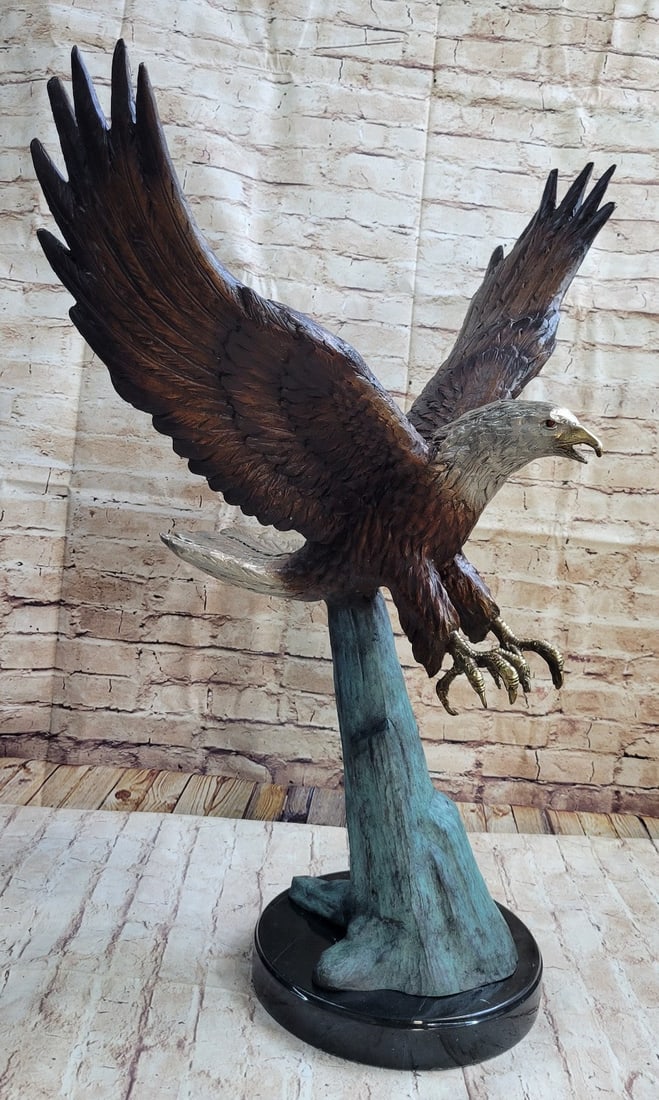American Eagle Swoops to Prey Bronze Sculpture: A large eagle swoops down towards the earth and prepares to pluck its meal from the ocean. His talons are spread and his legs are extended just waiting to grapple its prey. Eagles are known for their 