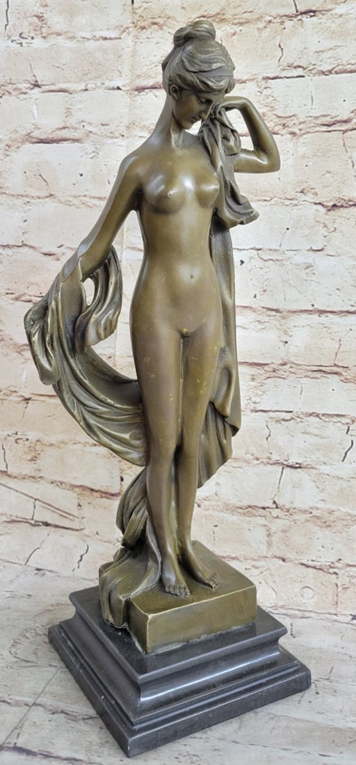 Sweet and Demure Nude Woman Bronze Sculpture: Sweet and demure the woman stands in the nude. Her hair is swept up in an elegant bun. A long, thick cloth hangs on her arm and swerves up to rest on her shoulder. She looks down wistfully, dreaming o