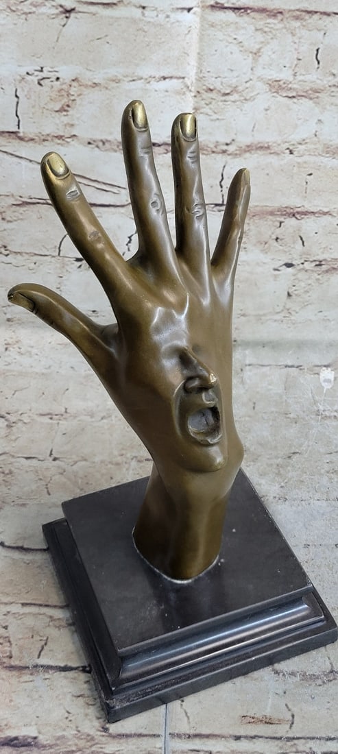 Hand With Face Bronze Statue: This extravagant and abstract piece was designed It features a realistic-looking human hand and forearm with the wrist slightly bent and fingers spread apart. The hand is offset by an intricate human 