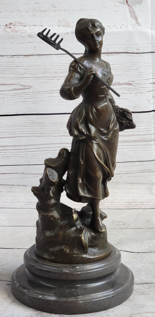 Lady Bronze Sculpture: After a long hard day in the wheat fields, a young girl makes her way home. With her rake in her hand and her bundle of wheat in the other she shares a slight smile and a worn look. This bronze