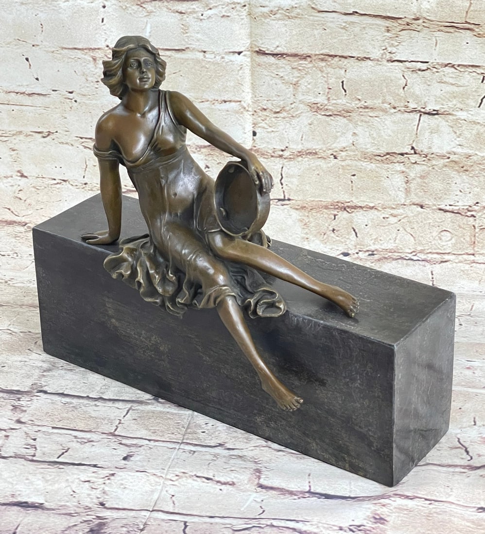 Young Maiden Perched with her Tambourine Bronze Sculpture: This young maiden sits perched with her tambourine, taking a break from captivating others with her beautiful music and dance. Her flowing dress slips off her shoulders revealing her breasts. This