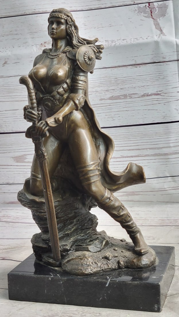 Amazon Warrior Bronze Sculpture: A sexy and tough Amazon warrior stands proudly holding her sword. Her other arm is tense, highlighting her sculpted arms. Her large breasts are dressed in a studded bikini. She is a fighter in the