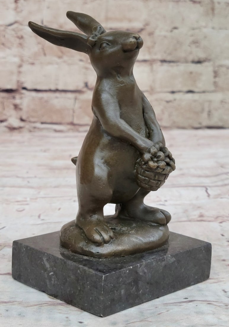 Lady Bunny With Flower Basket Bronze Sculpture: This cute and cuddly Lil lady looks up with the sweetest look and holds a tiny basket full of flowers in her tiny arms. This little bunny is the perfect touch of decor for a sweet and cute look. Her e