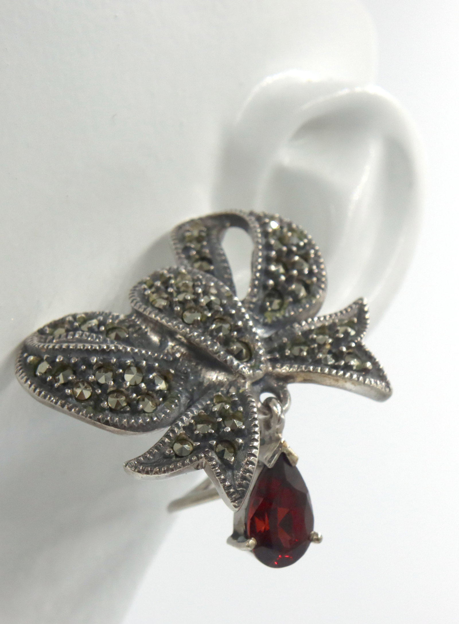 925 Sterling silver bow earrings: 925 Sterling silver bow earrings with pear shaped red cubic zirconia. The total weight of the earrings is 19.72 grams.