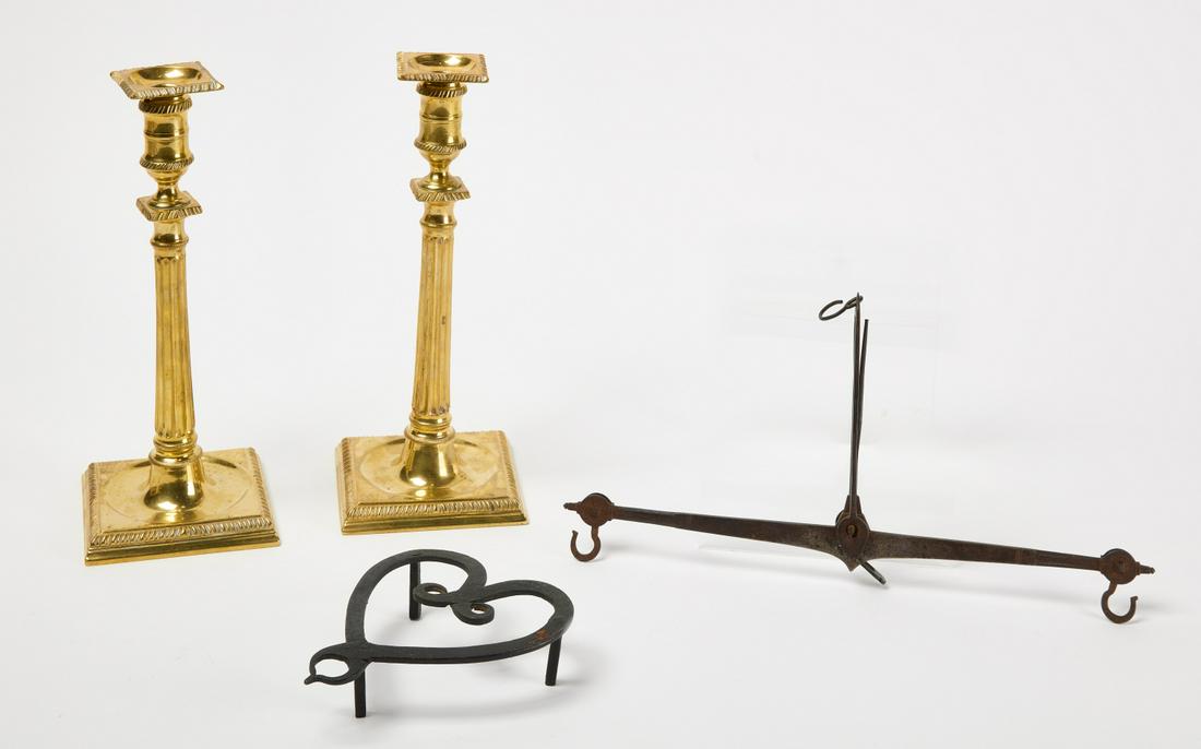Lighting Lot: Pair of early candlesticks. Brass. English. Together with an iron balance scale, and an iron heart trivet. Candlesticks H 11-1/8" W 4-1/2". Balance H 14-1/2". Trivet H 5-5/8" W 5". Condition: Original