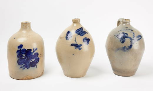 Three Stoneware Jugs: Three stoneware jugs. Two ovoid jugs with blue floral decoration circa 1830 together with stoneware jug with blue floral decoration, White and Son, Utica, New York. Ovoid jug: H 13" D 8". Ovoid jug: H