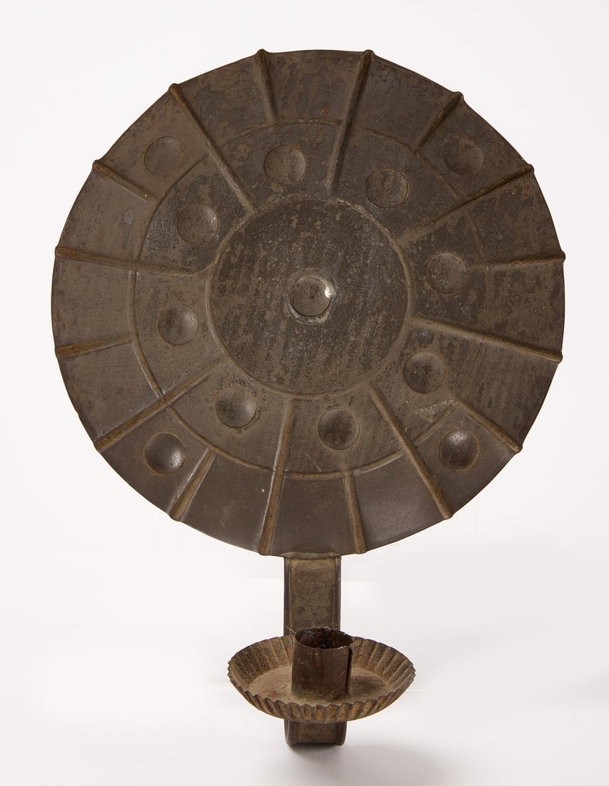 Early Tin Pie Plate Candle Sconce: Early tin pie plate sconce. Features embossed radiating lines and convex circles. Massachusetts. Late 18th century. H 12" W 8". Collection of Ron and Penny Dionne. Provenance: Note on back reads: "Thi