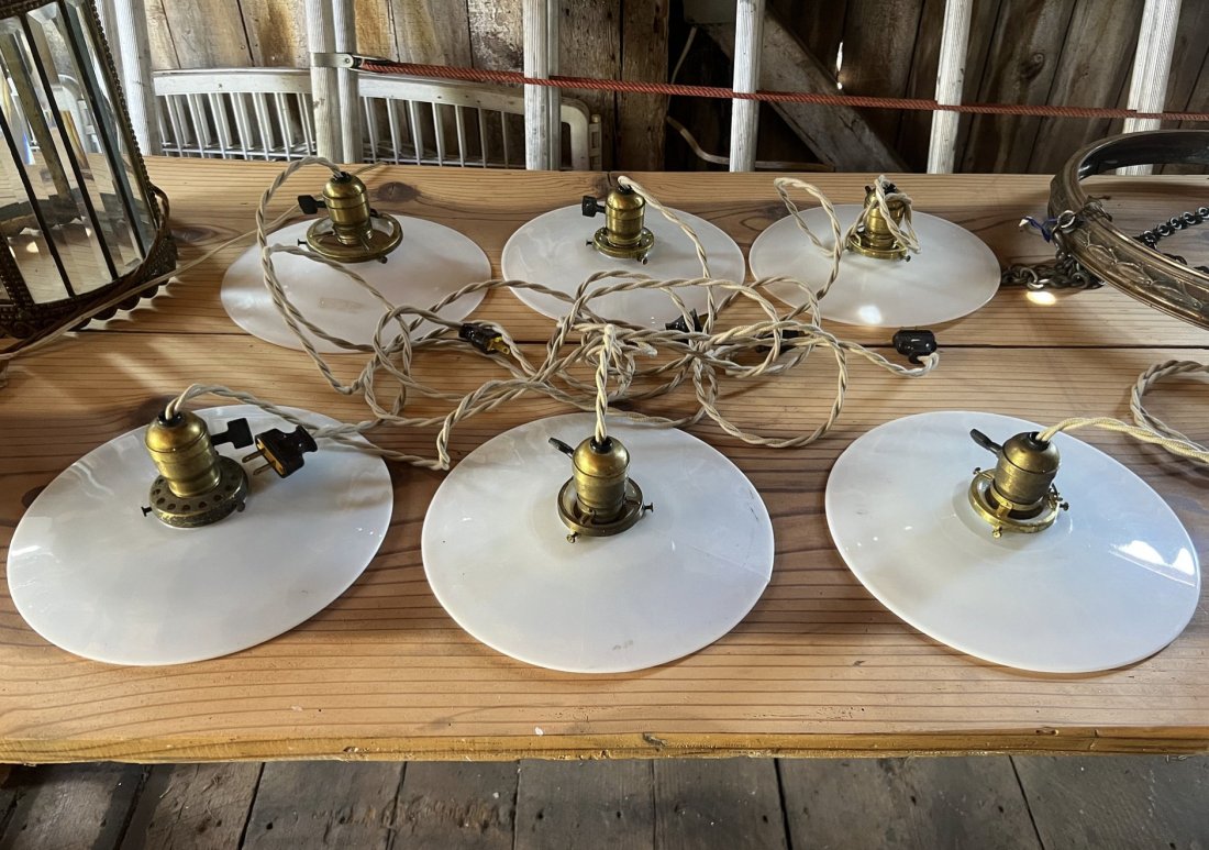 Group of Brass and Milk Glass Pendulum Lights with Additional Milk Glass Shades: Six brass pendulum lights with a total of 12 milk glass shades.Flat milk glass shades: 4- D 9-1/2" 1- D 10"Convex milk glass shades: 4- D 9-3/4" 1- D 10"Convex ruffle milk glass shades: 1- D 9-1/4" 1-