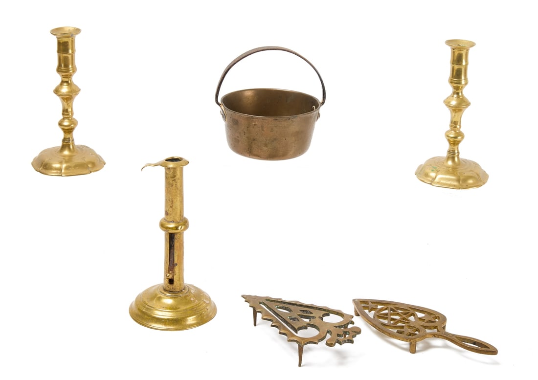 Brass Lot: Brass lot including a pair of trivets with hearts, pair of early candlesticks, single early push-up candlestick, and small brass pail. Early 18th–19th century. Trivets: L 7-1/4". Candl