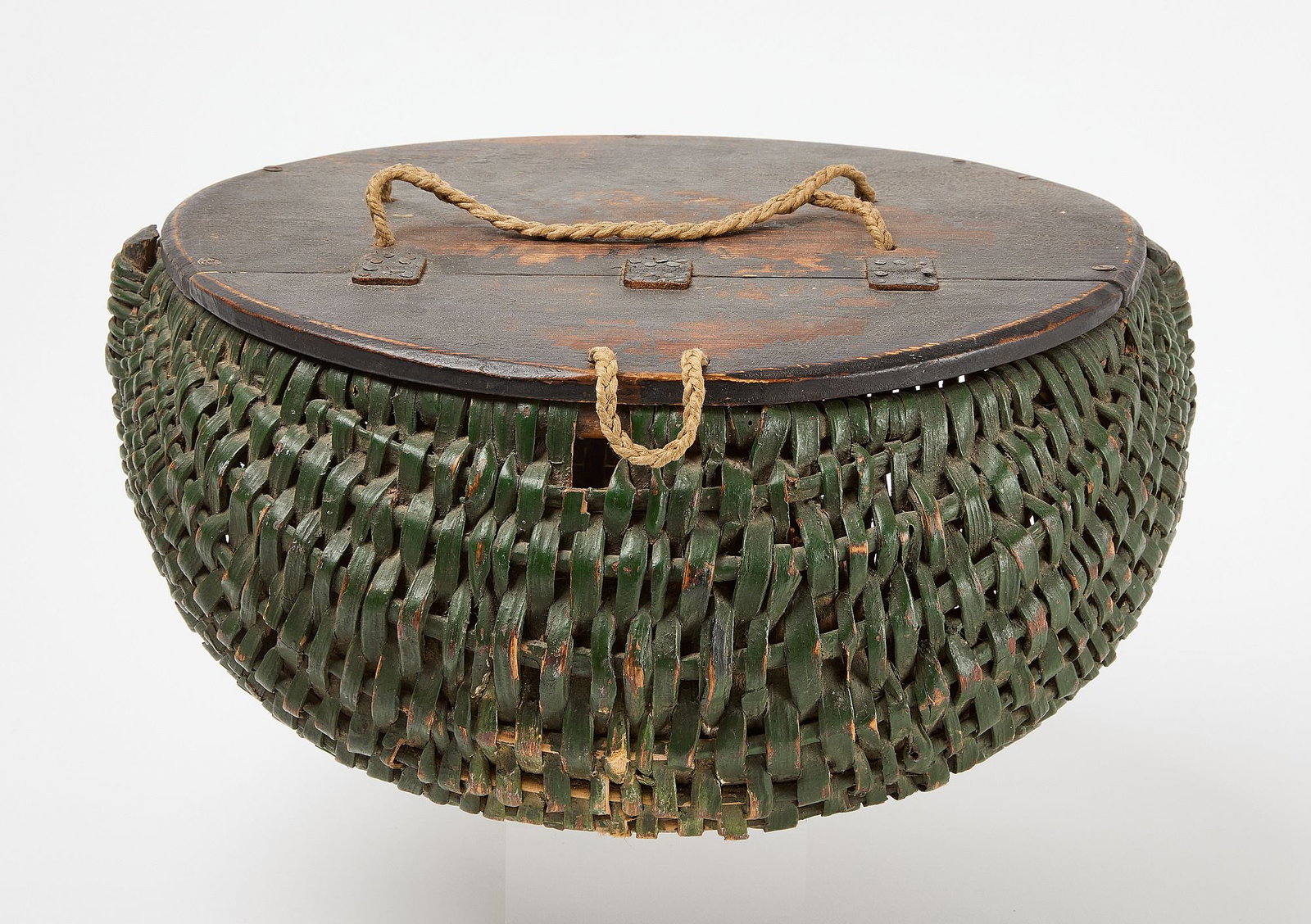 Painted Creel Basket: Painted creel basket in dark green paint with wooden lid to access the inside. Original paint. American, 19th century. H 8-1/2" D 17". Condition: Excellent condition with minor surface imper