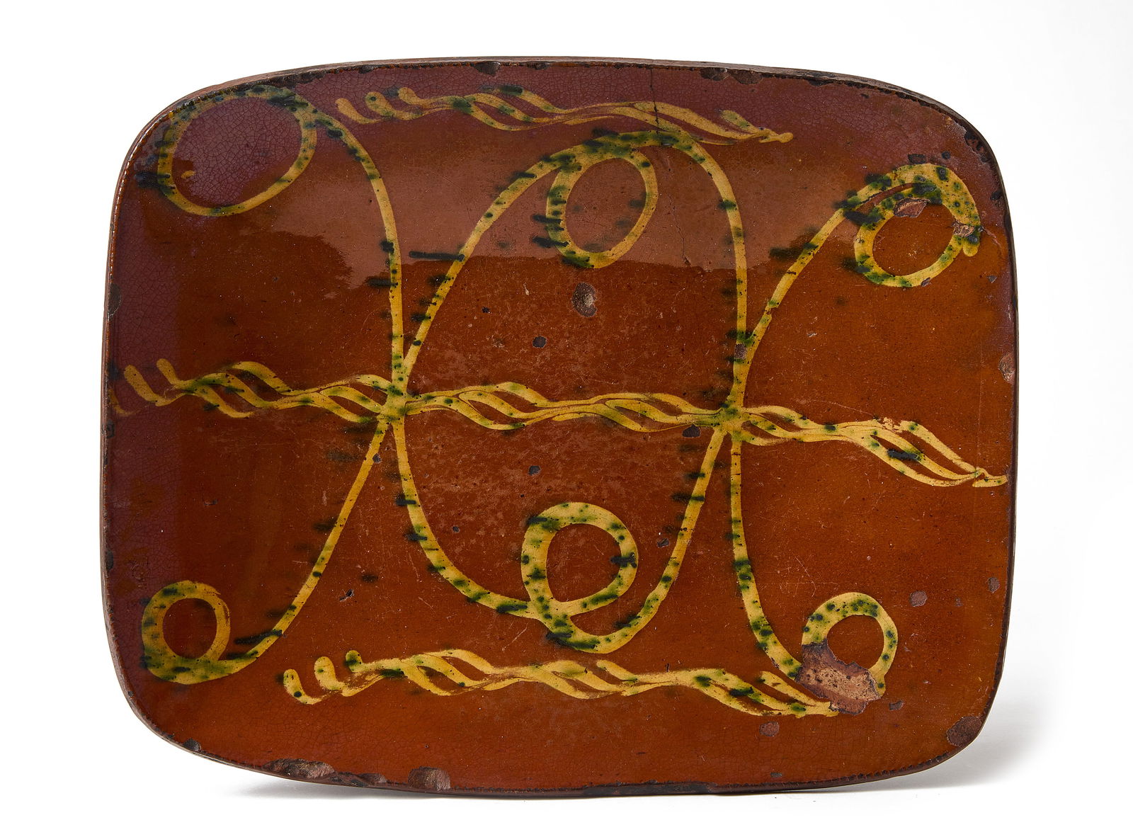 Redware Loaf Dish: Redware loaf pan with yellow and green slip decoration. Connecticut, circa 1830. Provenance: Private collector L 13-3/4" W 11-1/4". Condition: Hairline crack from edge to center and other minor imperf