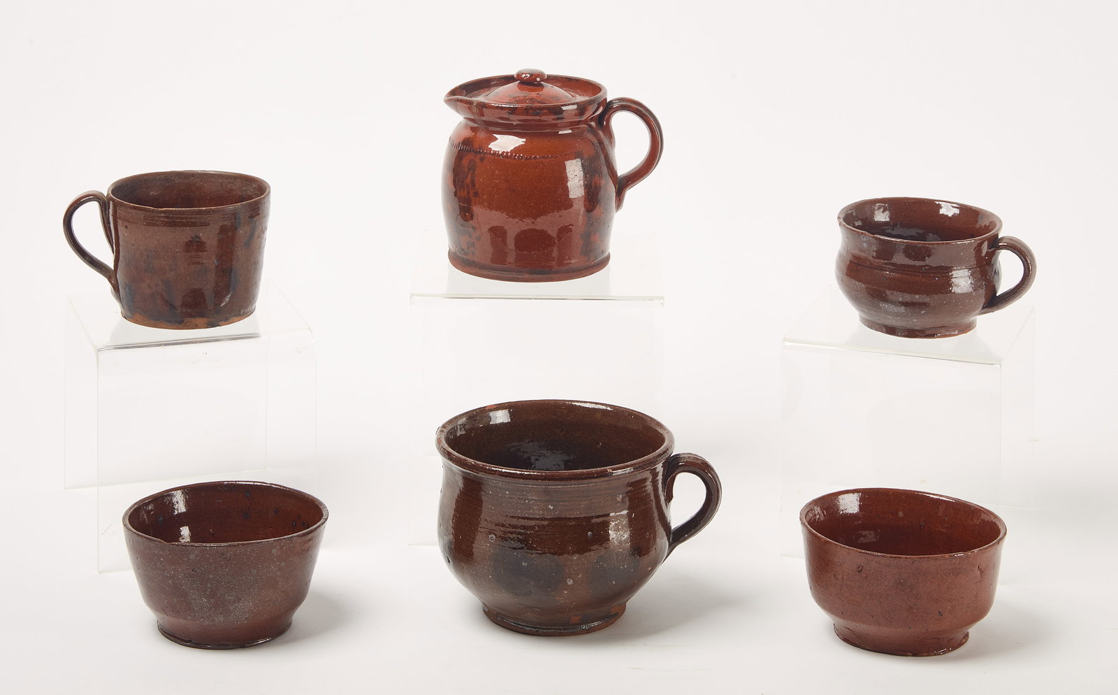 Redware Group: Six redware items. Two bowls and a covered pitcher. Pennsylvania. Together with two porringers and a mug. New England. Bowls: H 2-3/4" D 5-1/4". Pitcher: H 5" D 4-1/2". Porrin