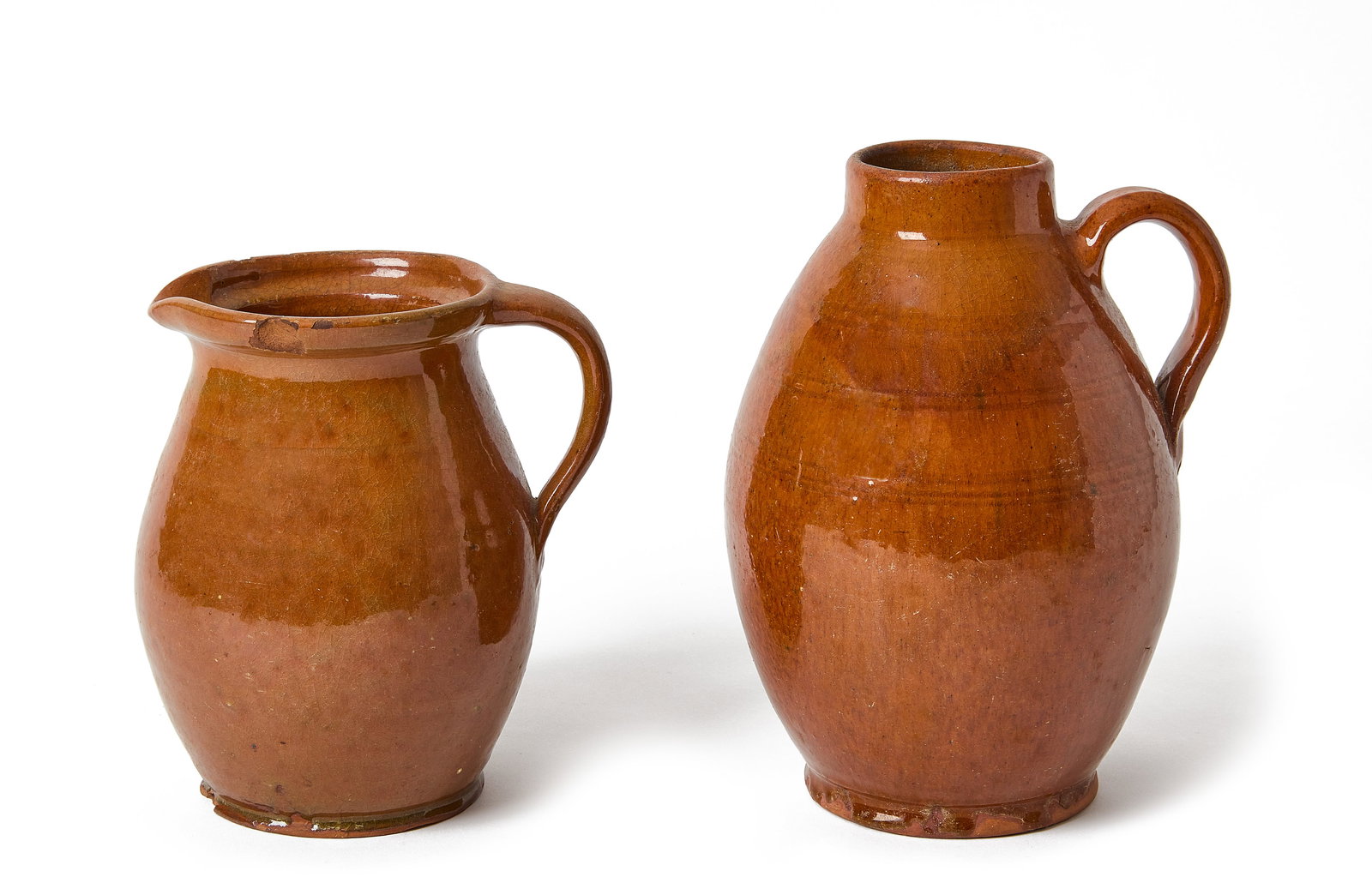 Two Redware Pitchers: Two redware pitchers. New England, circa 1825. Pitcher with spout identified as Osborn family potters, Danvers, Massachusetts. H 8-1/2". Osborn: H 6-3/4". Condition: Excellent with mino