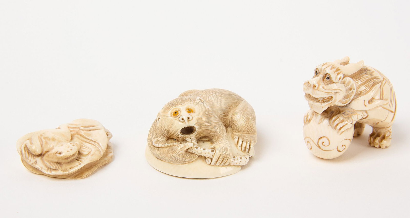 Three Netsuke with Animals: Three Netsuke with animals. Including one depicting monkey and squid on opposite sides. Signed. The second depicting turtle with ball. Signed. The third depicting frog on lily pad. Carved bone.&n