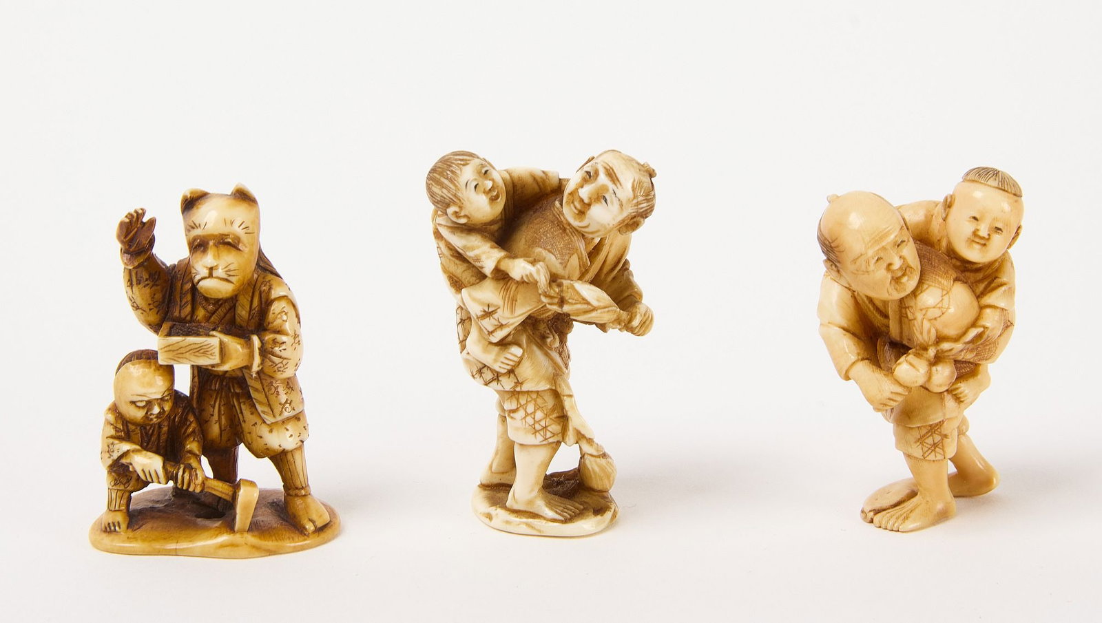 Three Netsuke of Men with Children: Three Netsuke of men with children. Two depict a man with child on his back. The third depicts man and child wearing masks. Carved bone. 19th to early 20th century, First man with child