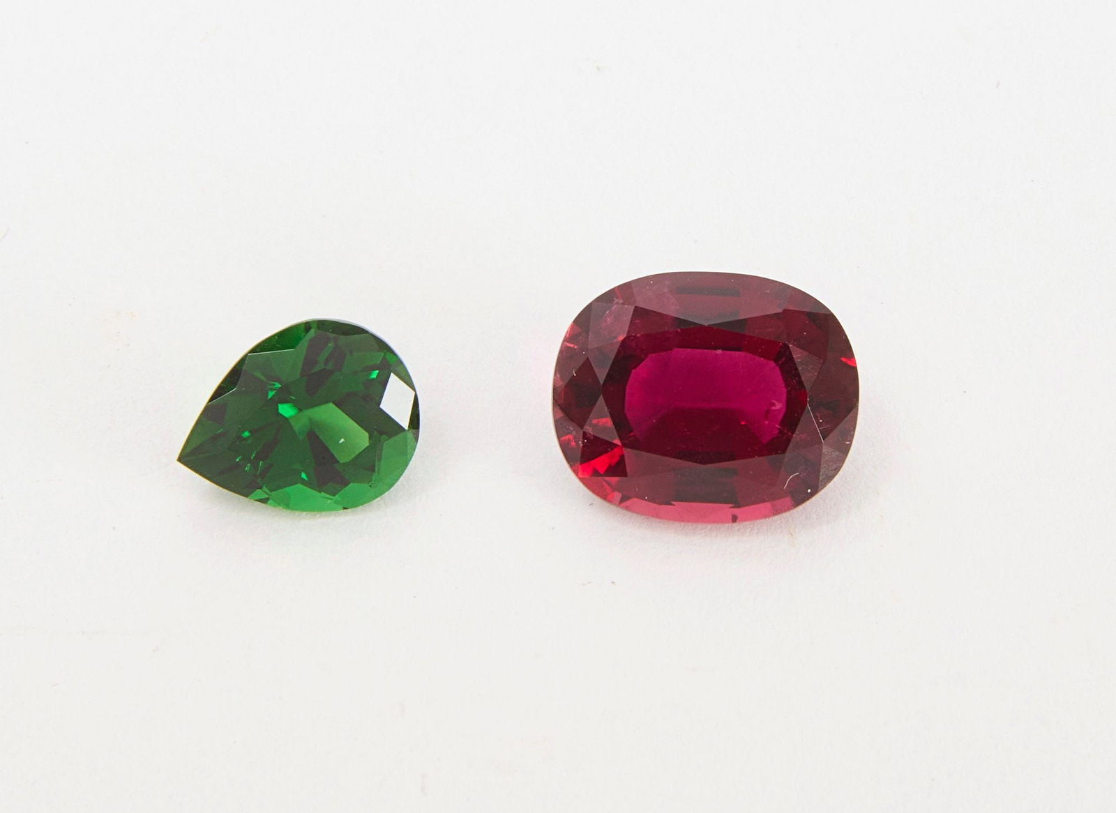 Chrome and Rubellite Tourmaline Gemstones: One loose, transparent dark green pear shape modified brilliant cut, natural chrome tourmaline. Together with one loose, transparent, oval mixed cut, natural rubellite gemstone. Chrome tourmaline: 2.0