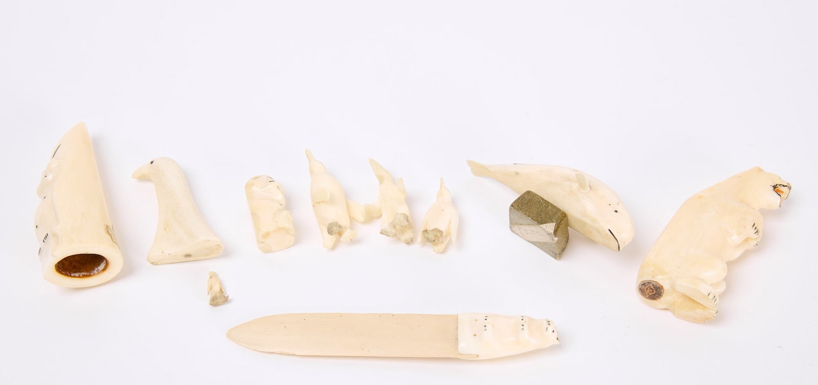 Group of Ten Carved Eskimo Bone Items: Group of 10 carved Eskimo bone items. Mid 20th century. Letter Opener: L 5-1/4, Bear H 3", Whale L 3-1/8", Tooth H 3-1/8". Other items range from 1"-1-7/8". Condition: Slight