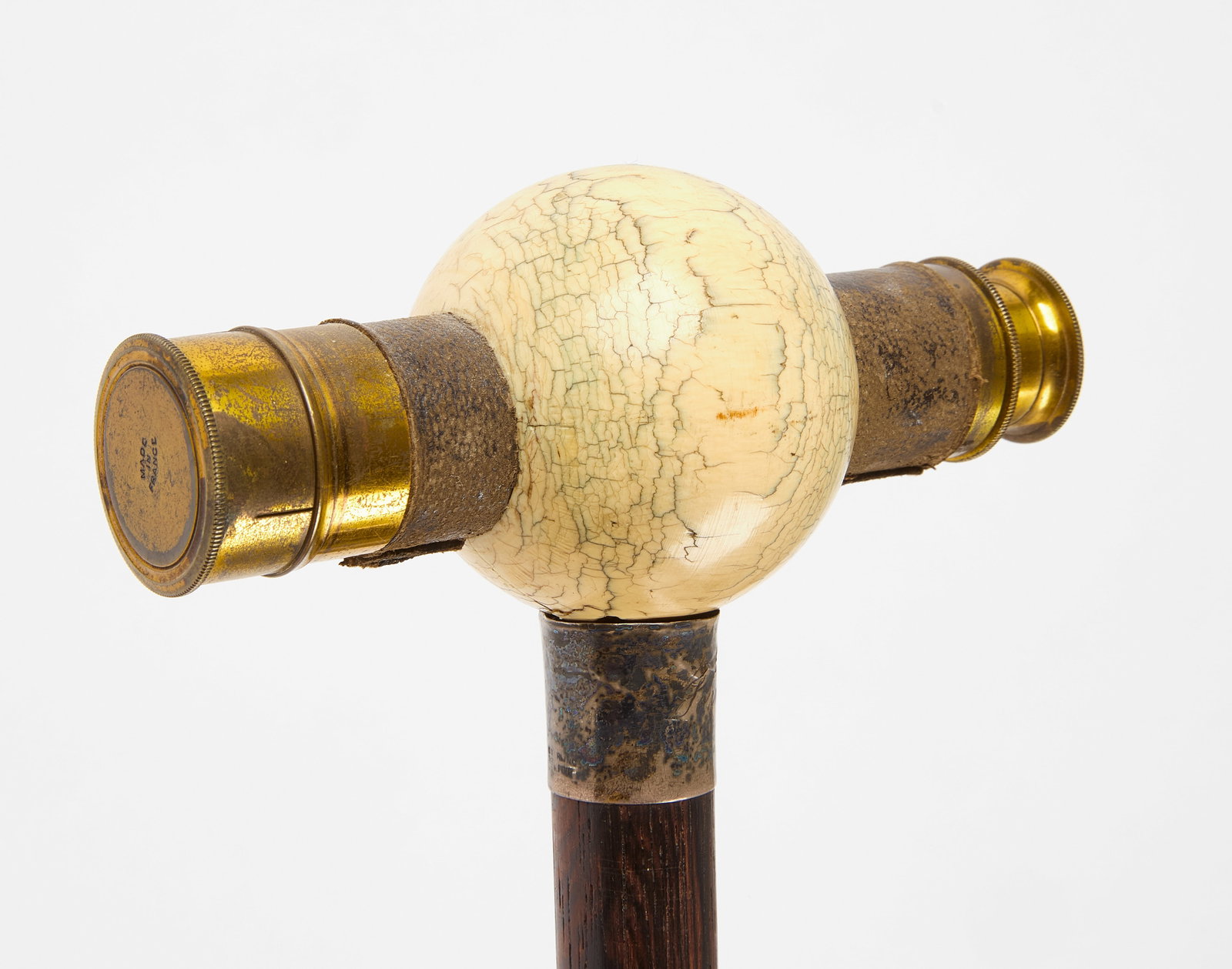 Scrimshaw Spyglass Walking Stick: Walking stick with spyglass handle. Scrimshaw sphere and French brass spyglass through middle. Sterling band near top of stick. Late 19th century. L 34". Condition: Split noted on under