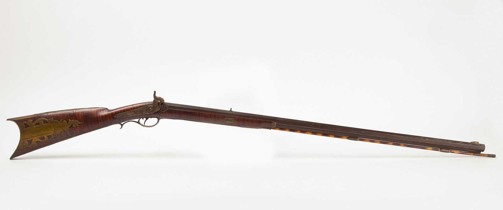 Kentucky Long Rifle: Kentucky style long rifle. Tiger maple stock with probably original ram rod. Octagon barrel, percussion fired. No maker noted. American, mid-19th century. Total: L 53". Barrel: 36-1/8". Cond