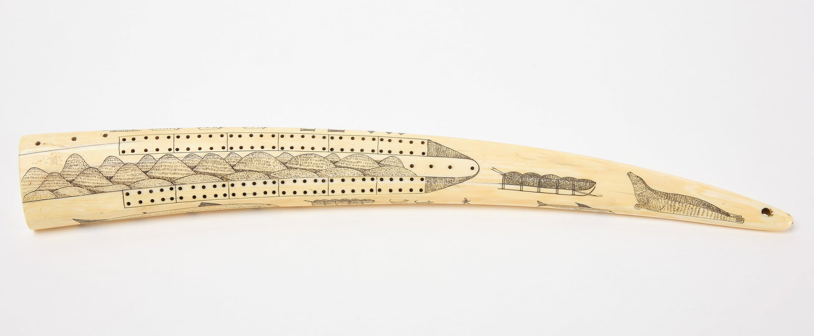 Scrimshaw Cribbage Tusk: Scrimshaw cribbage tusk. Alaska, circa 1920. L 21-1/2". Collection of Jeffery Myers. Condition: No damage noted. One wooden foot peg missing. Link to high-res images: https://www.dropbox.com