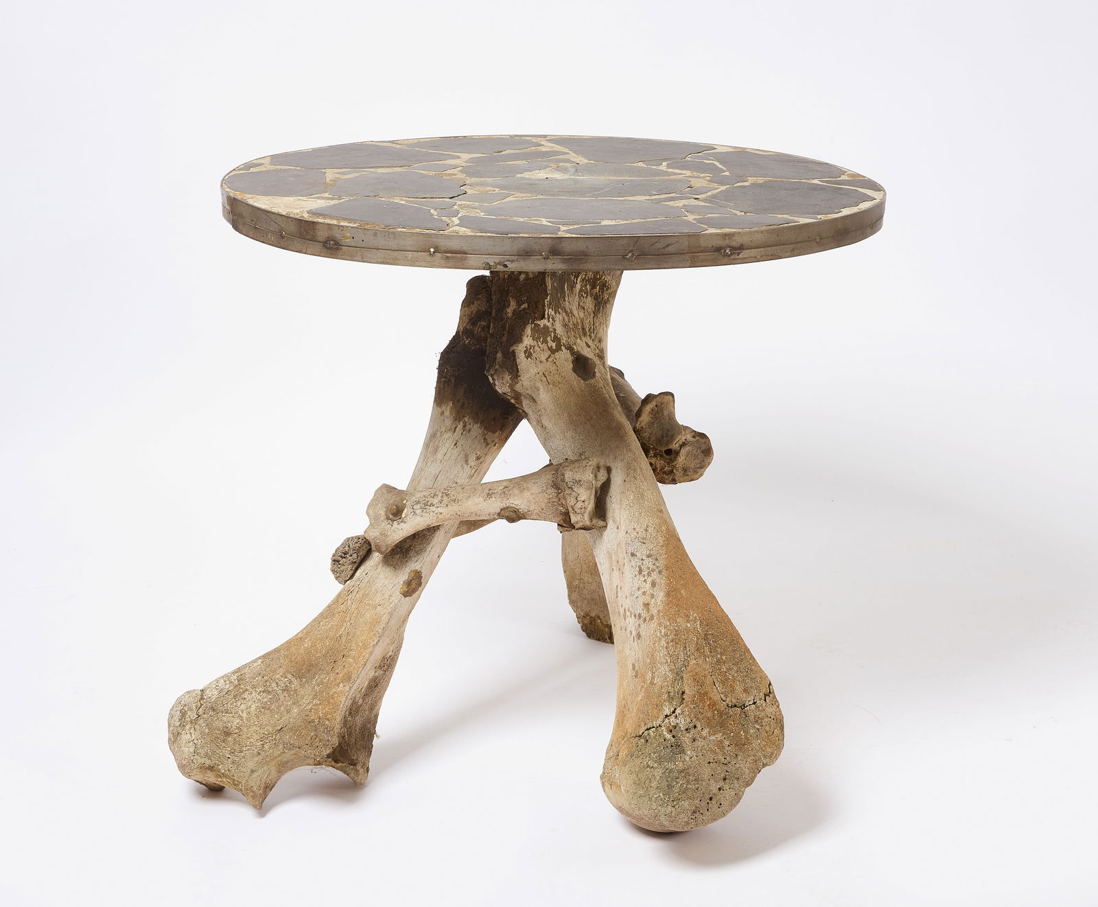 Bone Legged Table With Slate Mosaic Top: A vintage round topped table with a top made of cement and inset with random sized slate pieces, the whole with a strong metal band around the perimeter. The legs are made of bone. Constructed circa 1