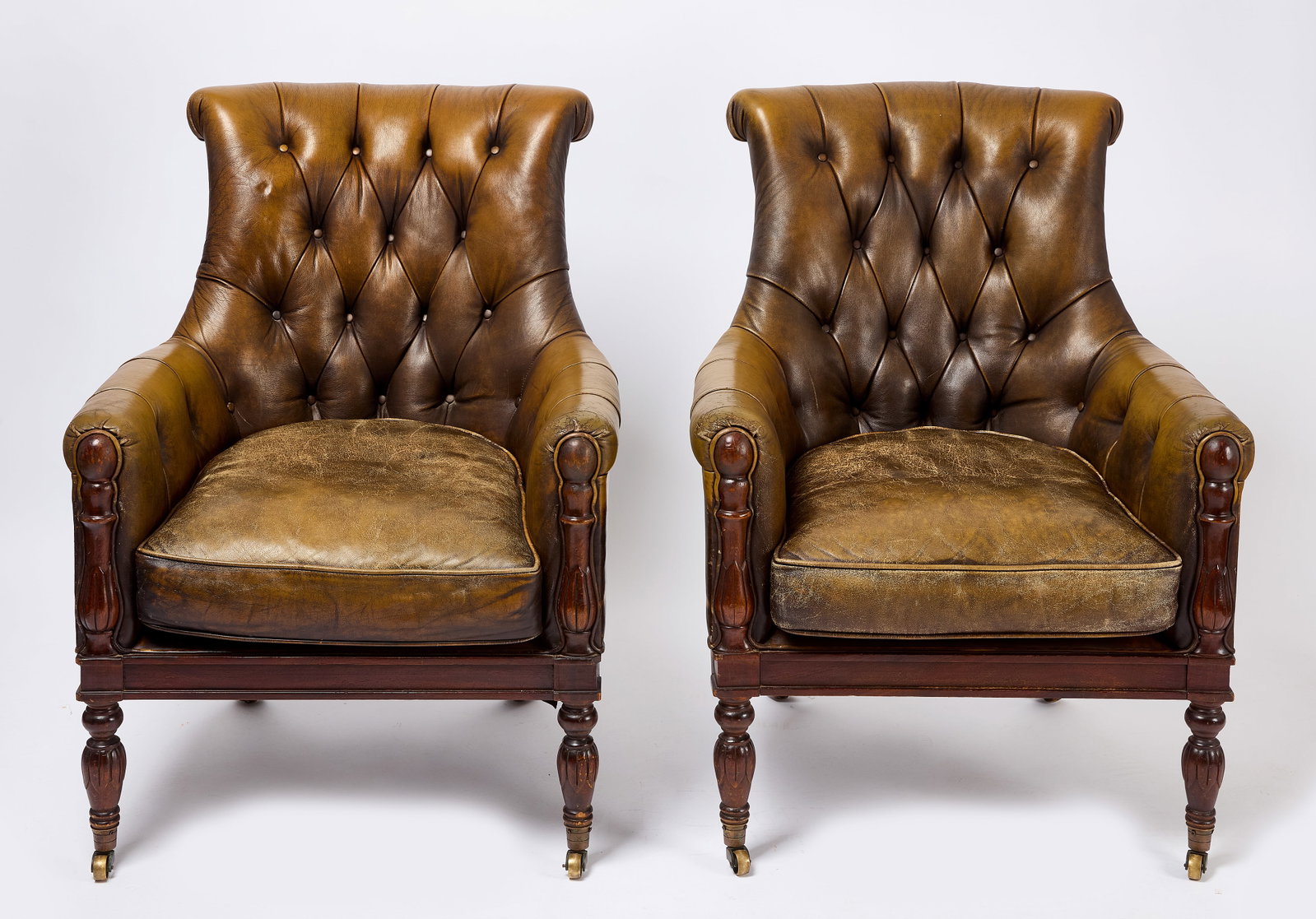 Pair of Leather Club Chairs: Pair of brown leather club chairs. Front two legs on castor wheels. H 38 in. W 29 in. D 25 in. Condition: Surface imperfections and scuffs to leather from use. Link to hi-res images: https://www.dropb