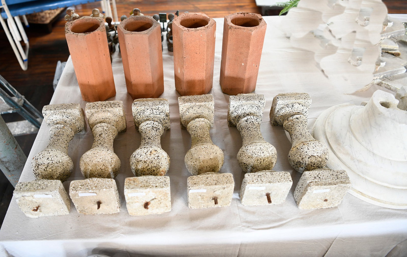 Group of Cast Stone Marble Items: Two marble column bases, four terra cotta wine bottle shipping holders, six cast stone pillars. Column bases H 8.5 in. W 16.5 in. Terra Cotta: 12 in. Stone Pillars: H 14 in. 