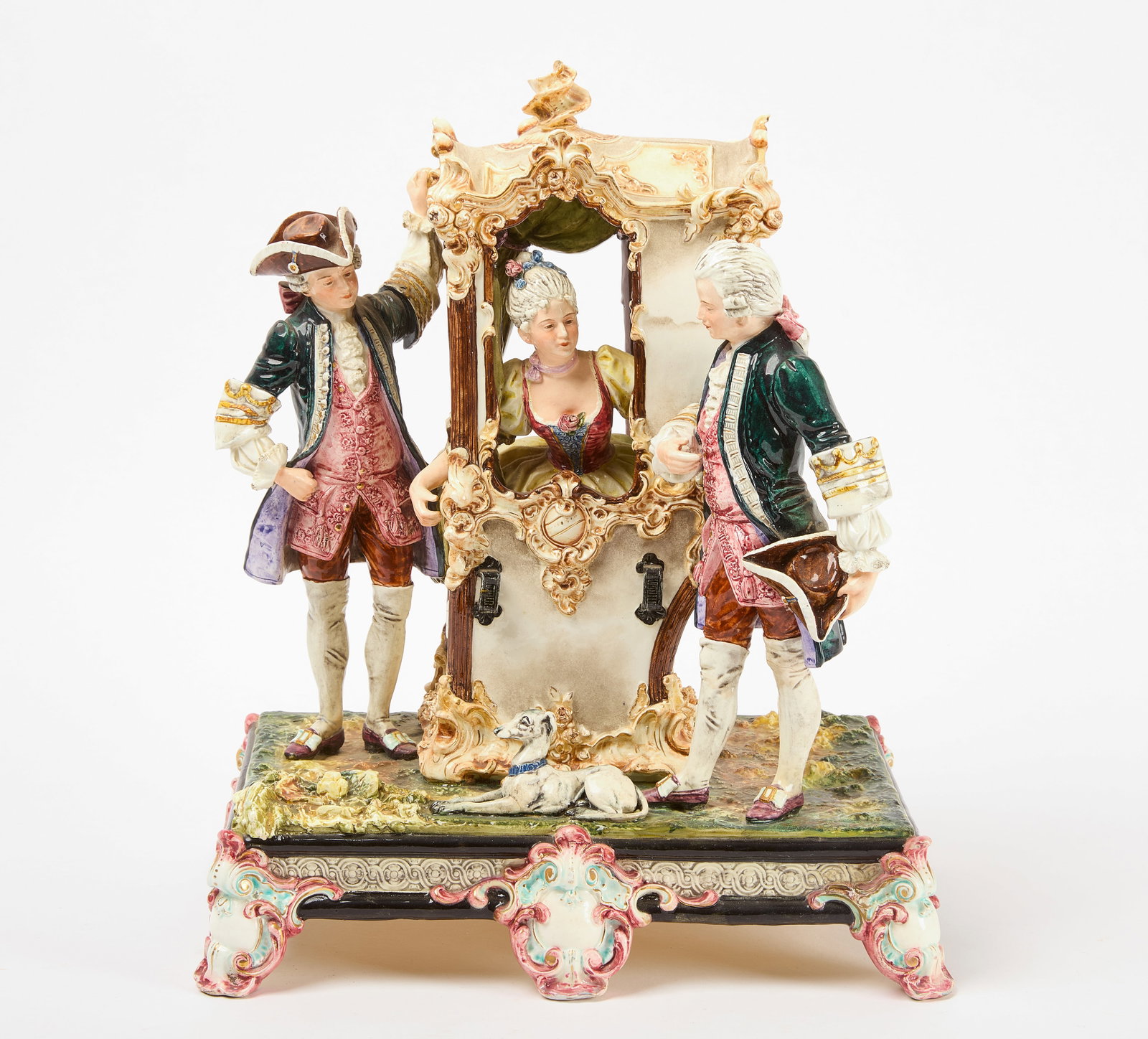 Large Porcelain Figurine - Lady in Sedan Chair with Two Courters: A large porcelain figurine depicting a woman in a sedan chair flanked by two courters, all in 18th century period dress. The figure has a rectangular base with scrolled feet. Germany, 19th century.&nb