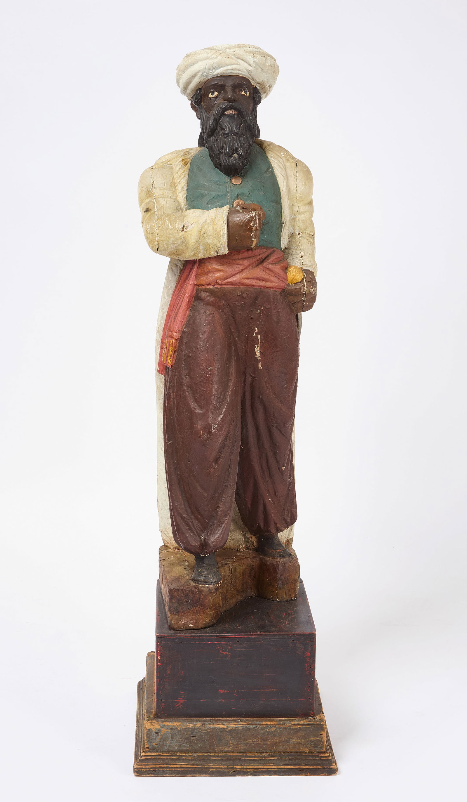 Turk Tobacconist Trade Figure: Turk tobacco store figure. Carved and painted wood attached to wood pedestal. Depicts a bearded man in a turban holding a dagger to his side. American, early third quarter of the 19th century. (