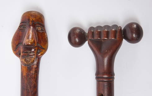 Folk Art Walking Stick and Root Carved Walking Stick: A clutching hand folk art walking stick. Together with a root carved walking stick with carved face handle. American, circa 1900. L 34-1/2 in. and L 34-3/8 in. Condition: Minor surface imperfections.