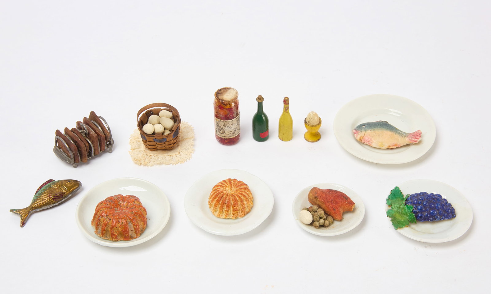 Group of Dollhouse Food: Group of dollhouse food including plated soft paste food, basket of eggs, bottles, and other items as shown. Continental, 19th century. Smallest: H 1 in. Largest: D 2-3/4 in. Provenance: Collection of