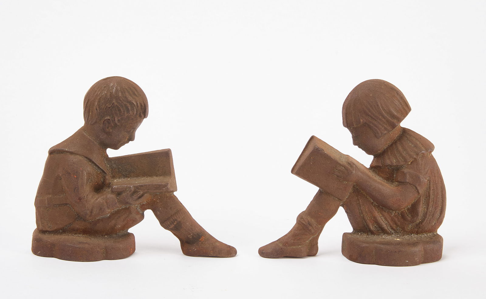 Pair of Bookends - Boy and Girl Reading: Pair of cast iron bookends depicting a boy and girl reading. American, early 20th century. H 5-1/2 in. W 6-1/2 in.