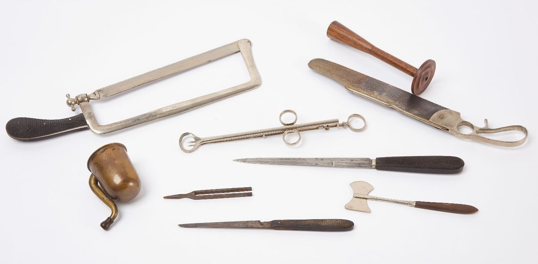 Group of Medical and Surgical Implements and Cased Sets: Group of medical and surgical implements. Brass 'tin ear' device, a wooden stethoscope, tonsil guillotine, wood-handle double edged saw, amputation knife, capital saw, small tuning fork, a