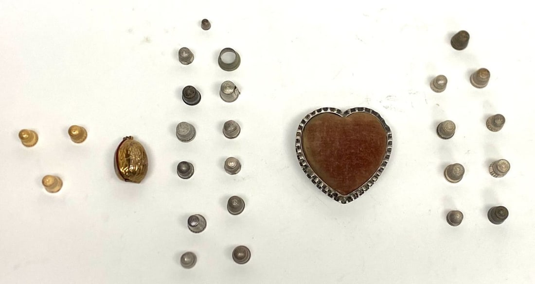Sewing Group with Sterling and Gold: Sewing group with a sterling heart-shaped pin cushion, and 25 thimbles. 10k (acid tested): 2.5 dwt.14k (acid tested): 5.2 dwt.Sterling (stamped): 1.4 ozt.Pin cushion: 2.61 ozt. 