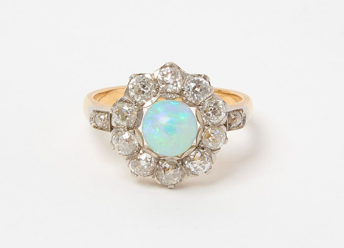 14K Yellow Gold Opal and Diamond Ring: 14K yellow gold ring set with (1) opal cabachon (AA quality). Approx. total weight is 1.20 carats. Opal is surrounded by (10) round, old miner cut diamonds in a halo setting, and (1) round old miner