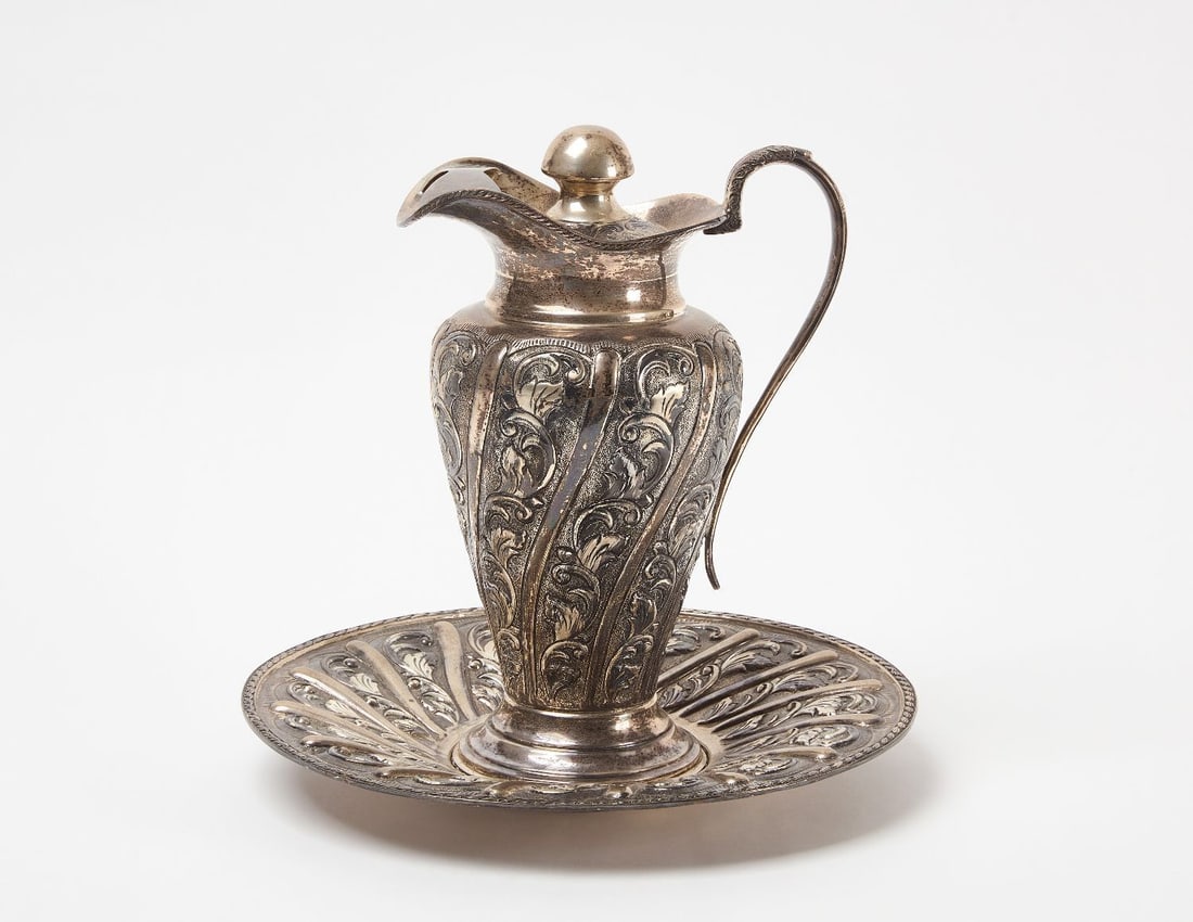 900 Silver Pitcher and Plate Set: Silver-Plate style pitcher and plate set. 64.185 ozt (combined). Marked 900 silver.Plate: H 1 in. D 12-3/4 in. Pitcher: H 12 in.