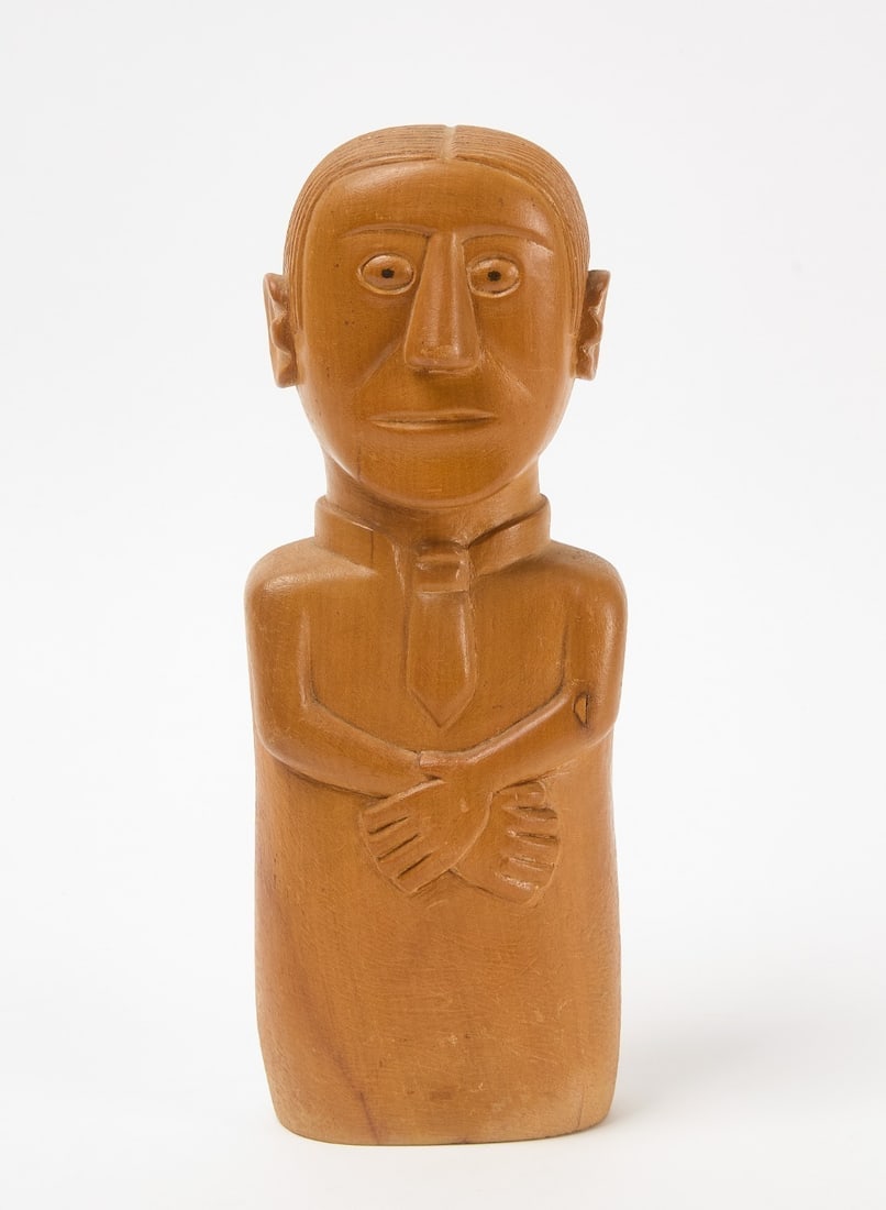 Folk Art Bust of a Man: Folk art bust of a man with folded hands, wearing a tie. Carved, solid wood with painted eyes.H 11-1/2 in. W 4-1/8 in. D 3-7/8 in.