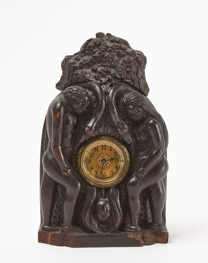Adam and Eve Figural Mantle Clock: Hand-carved figural mantle clock, featuring Adam and Eve figures, two serpents, the tree of knowledge and the forbidden fruit. Wood with brass clock composition at center. Europe, late 19th to