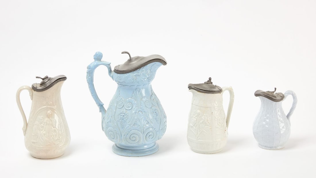 Four English Pitcher with Pewter Lids: Four ceramic pitchers with pewter lids. The first a Baccus pitcher in blue, attributed to Ridgeway pottery. Together with three white glased pitchers. English, 19th century.Baccus pitcher: H 9-5/8 in.