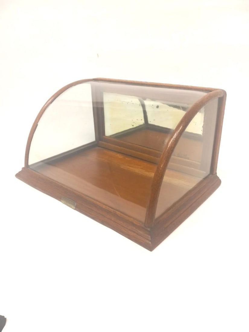 J. Riswig Curved Front Showcase: J Riswig (Chicago) curved front showcase with hinging back door and mirrored back. Glass and wood. American, circa 1930. H 9 in. W 18-1/2 in. D 12-1/4 in.
